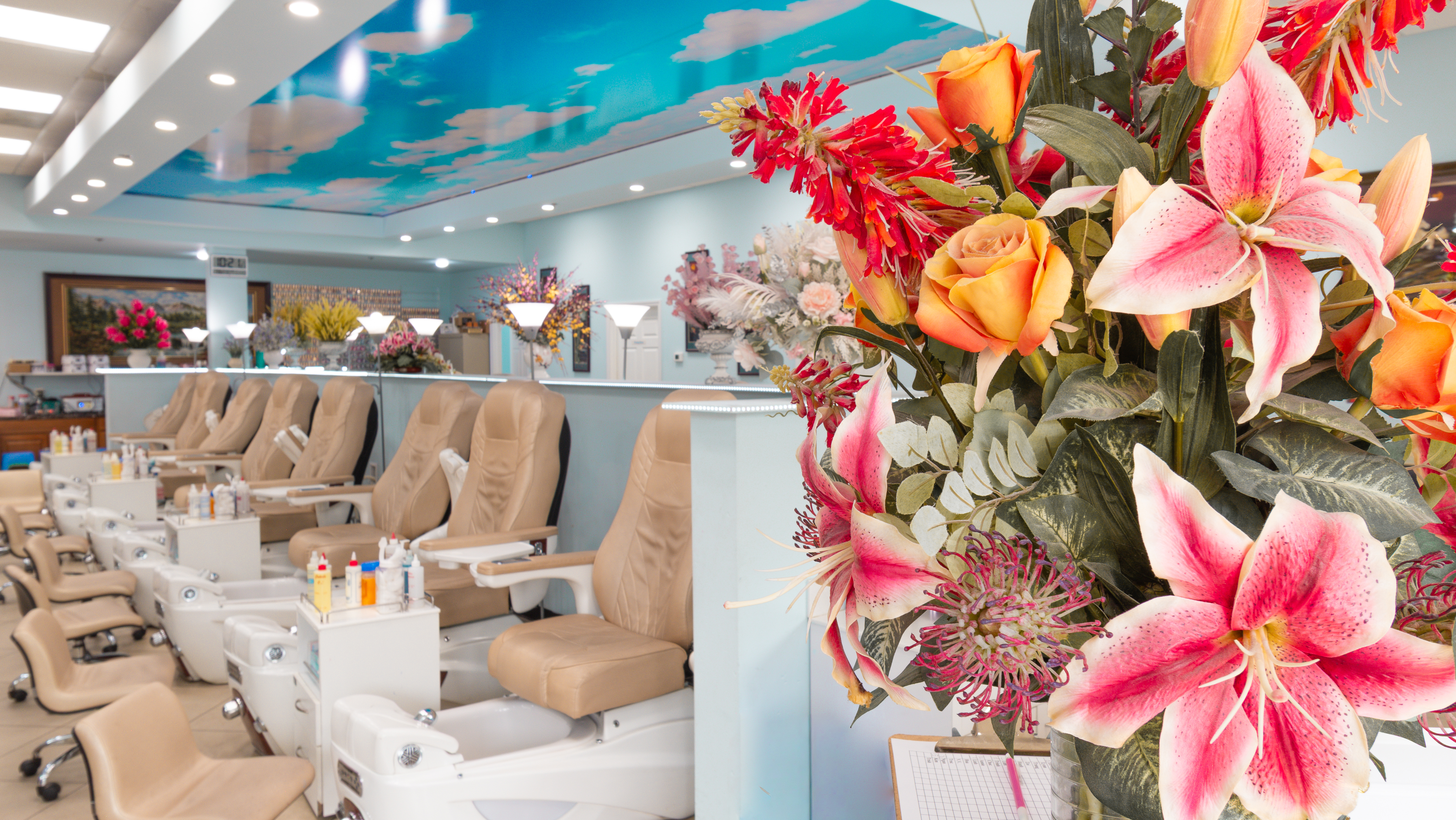 Blue-sky ceiling over the salon floor with floral arrangements